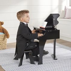 a young boy sitting at a piano in a child's room with stuffed animals