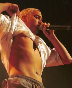 a shirtless man holding a microphone in his right hand and singing into the microphone