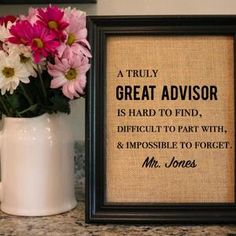 a vase filled with pink and white flowers next to a framed quote