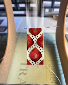 a piece of beaded art sitting on top of a wooden chair