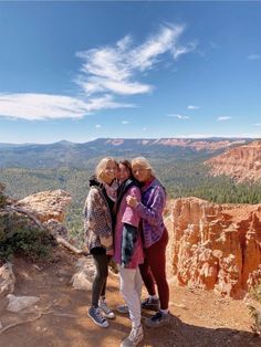 three women are standing on the edge of a cliff