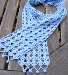 a blue crocheted scarf sitting on top of a wooden bench