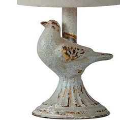 a white bird lamp sitting on top of a table next to a light fixture with a beige shade