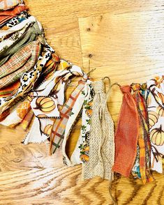 an assortment of scarves are laid out on a wooden surface, including one with oranges and yellows