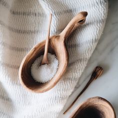 two wooden spoons filled with sugar on top of a white towel next to each other