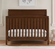 a baby crib in a room with white walls and wooden floors, along with a teddy bear