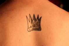 the back of a woman's shoulder with a tattoo of a crown on it