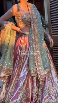 a woman in a red and gold lehenga with her hands on her hips