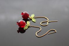 This image features a beautiful jewelry set inspired by pomegranates, crafted from resin with stainless steel components. The set includes earrings and a matching necklace, each designed with a deep red resin pomegranate as the focal point. The pomegranates are detailed with small green leaves, also made from resin, giving them a lifelike appearance. The earrings hang elegantly from gold-toned stainless steel hooks, while the necklace features a delicate gold-toned chain. The vibrant red of the pomegranate contrasts beautifully with the golden chain and hooks, creating a striking and elegant piece that would be perfect for adding a touch of nature-inspired charm to any outfit. This jewelry set is durable due to the stainless steel parts, making it a lasting addition to your collection. The Enamel Drop Earrings As A Gift, Elegant Resin Drop Earrings, Enamel Drop Earrings For Gifts, Elegant Nickel-free Resin Jewelry, Elegant Dangle Resin Jewelry, Red Round Resin Jewelry, Red Resin Round Jewelry, Elegant Resin Dangle Jewelry, Elegant Amber Resin Jewelry