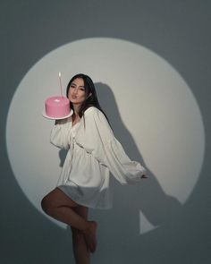 a woman holding a cake with a candle on it in the shape of a circle