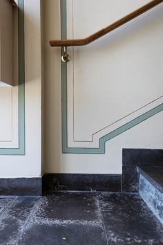 a black and white tiled floor next to a wall with green trimmings on it