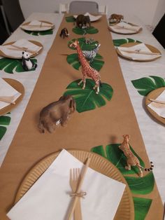 the table is set with paper plates, napkins, and animal figurines