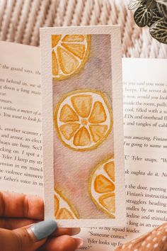 a person is holding an open book with oranges on it and the pages have been drawn