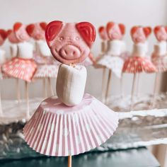 there is a pig on top of a cupcake with marshmallows in the background