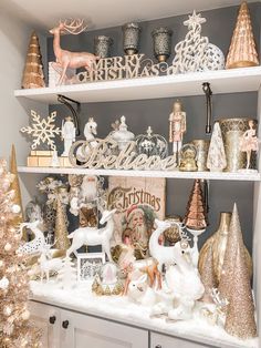 a shelf filled with christmas decorations and figurines on top of white cupboards