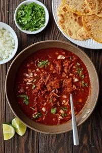 a bowl of chili with tortilla chips and limes on the side next to it