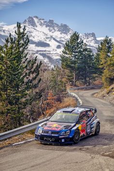 a rally car driving down a road with mountains in the background