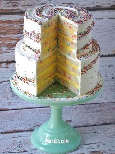 a three layer cake with sprinkles is on top of a green pedestal