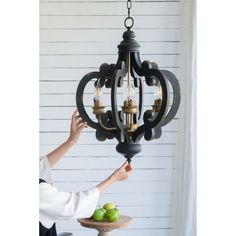 a chandelier hanging from the ceiling with apples in front of it on a table