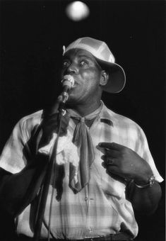 a man in a hat and tie singing into a microphone