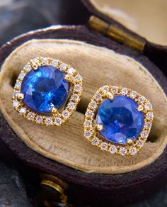 pair of blue sapphire and diamond stud earrings in wooden box with brown velvet case on table