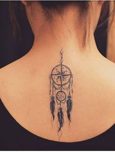 the back of a woman's neck with a tattoo on it that has an image of a dream catcher