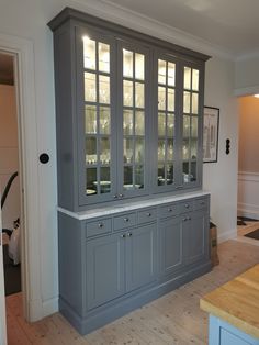 a large gray china cabinet with glass doors on the top and bottom, in a kitchen