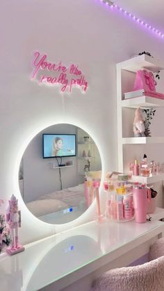 a room that has a mirror and lights on the wall in front of it with pink decorations