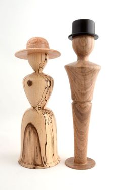 two wooden figures are standing next to each other, one wearing a hat and the other with a top hat on