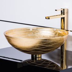 a bowl shaped sink sitting on top of a black counter next to a faucet