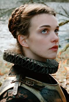 a woman with braids on her head wearing armor and looking off into the distance