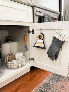 an open cabinet with gloves and other items on the shelf next to it, in a kitchen