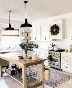 a large kitchen with white cabinets and an island in the middle, surrounded by potted plants