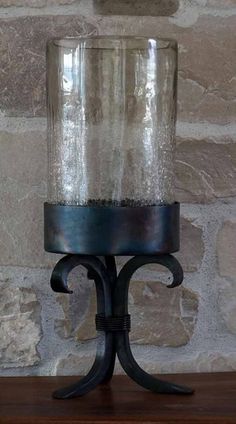 a glass jar sitting on top of a wooden table next to a stone wall and shelf