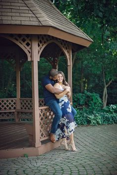 a couple hugging each other in front of a gazebo