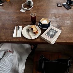 a wooden table topped with a plate of food and drinks next to a book on top of it