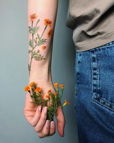 two people holding flowers on their hands with tattoos on them, both showing the same flower