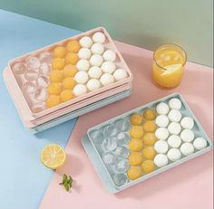 two plastic trays filled with different types of candies next to a glass of orange juice