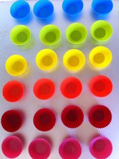 colorful cupcake liners arranged in rows on white surface with red, yellow, and blue cups