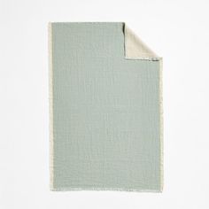 a green and white blanket folded on top of each other with a piece of cloth underneath it