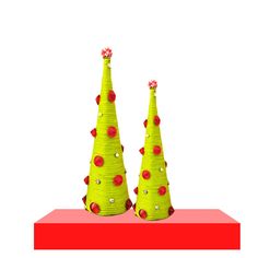 two green christmas trees sitting on top of a red table