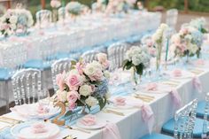 the tables are set with blue and white linens, silverware, and pink flowers