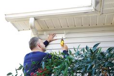 a man in blue shirt holding a yellow and black object on the side of a house