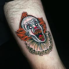 a creepy clown tattoo on the leg of a man's arm with red hair