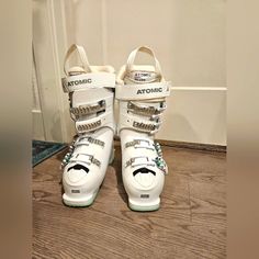 a pair of white ski boots sitting on top of a wooden floor