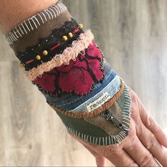 a person's hand holding several different bracelets