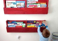 a young boy is playing with books on the wall