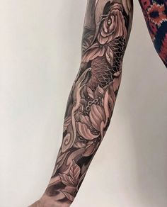 a woman's leg with flowers and fish tattoo on her left arm, next to a white wall