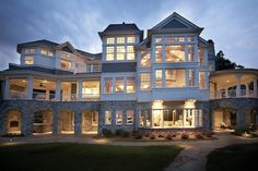 a large white house with lots of windows and lights on it's front porch