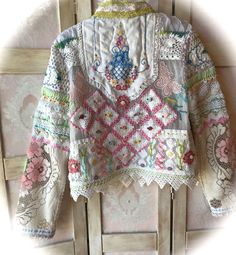 an embroidered jacket hanging on a wooden door with white wallpaper and floral designs in the background